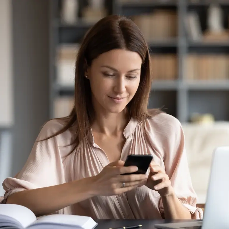 Woman-holding-mobile-device-at-desk