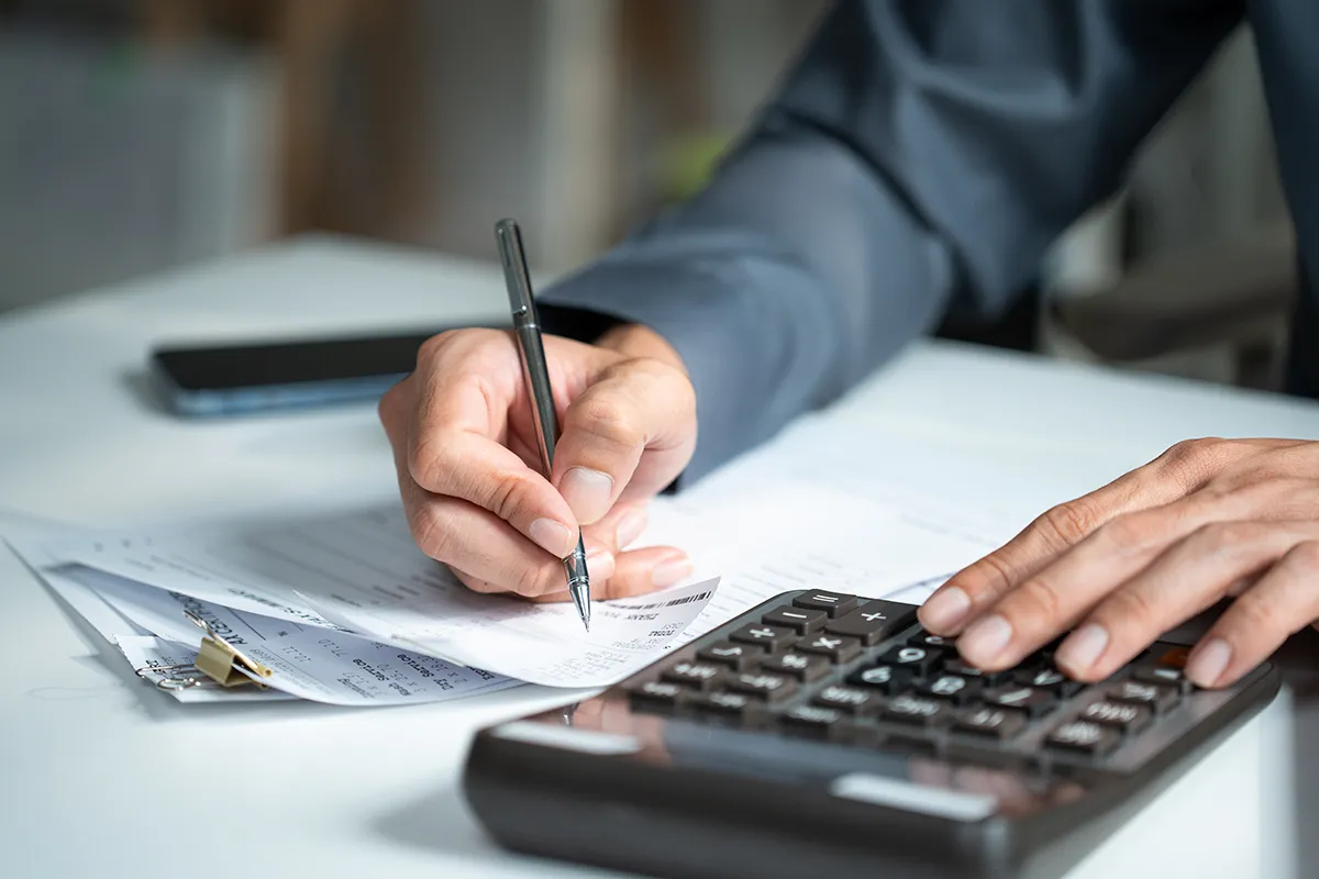 close-up of a man's hands with a calculator and financial documents